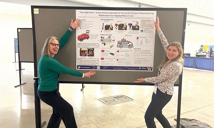 Heather and Mia stand at the poster