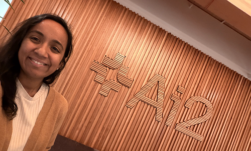Arnavi standing in front of AI2 sign