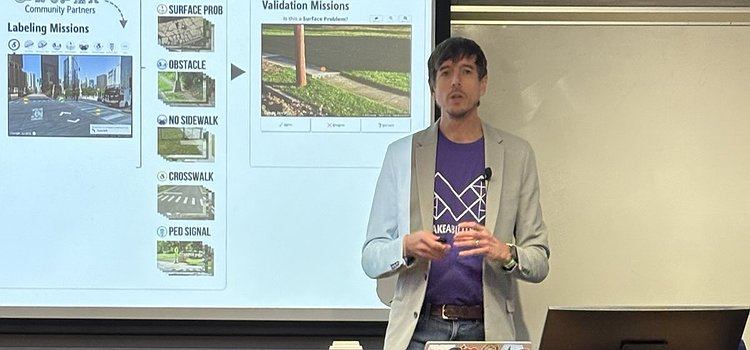 Jon standing in front of a UMN lectern giving his Distinguished Lecture with a slide in the background
