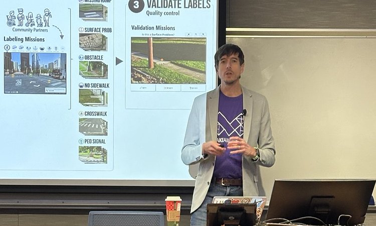 Jon standing in front of a UMN lectern giving his Distinguished Lecture with a slide in the background