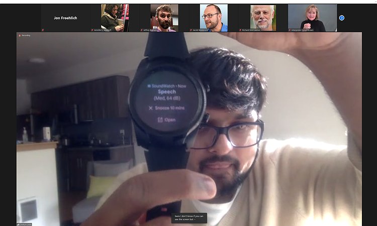 DJ holding an Android watch running SoundWatch that shows Speech has been recognized (at 64 dB). The alert can be snoozed for 10 minutes