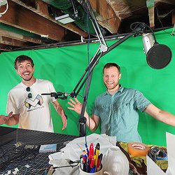 Brent and Jon standing in front of Jon's green screen and making funny gestures/faces