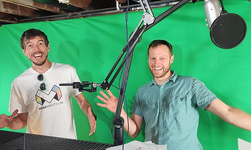 Brent and Jon standing in front of Jon's green screen and making funny gestures/faces