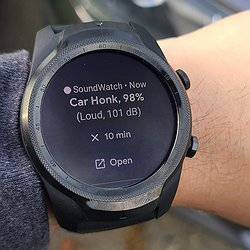 Image shows a person wearing an Android smartwatch with the SoundWatch user interface, which shows a "Car Honk" recognized sound with 98% accuracy and 101 decibels.