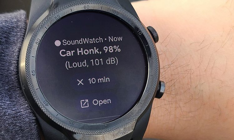 Image shows a person wearing an Android smartwatch with the SoundWatch user interface, which shows a "Car Honk" recognized sound with 98% accuracy and 101 decibels.