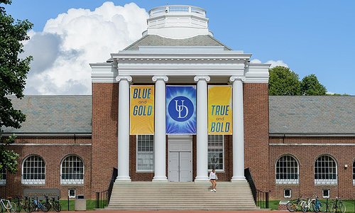 Picture of a University of Delaware campus showing a brick building and some UDelaware banners
