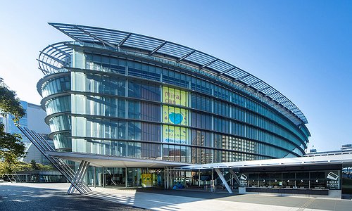 The Miraikan museum building. A modern oval shaped building with a sleek glass exterior.