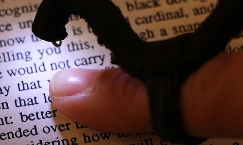 Image shows a small camera on top of the user's finger, self-illuminated and pointed down towards the text on a printed book.