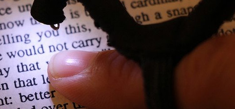 Image shows a small camera on top of the user's finger, self-illuminated and pointed down towards the text on a printed book.