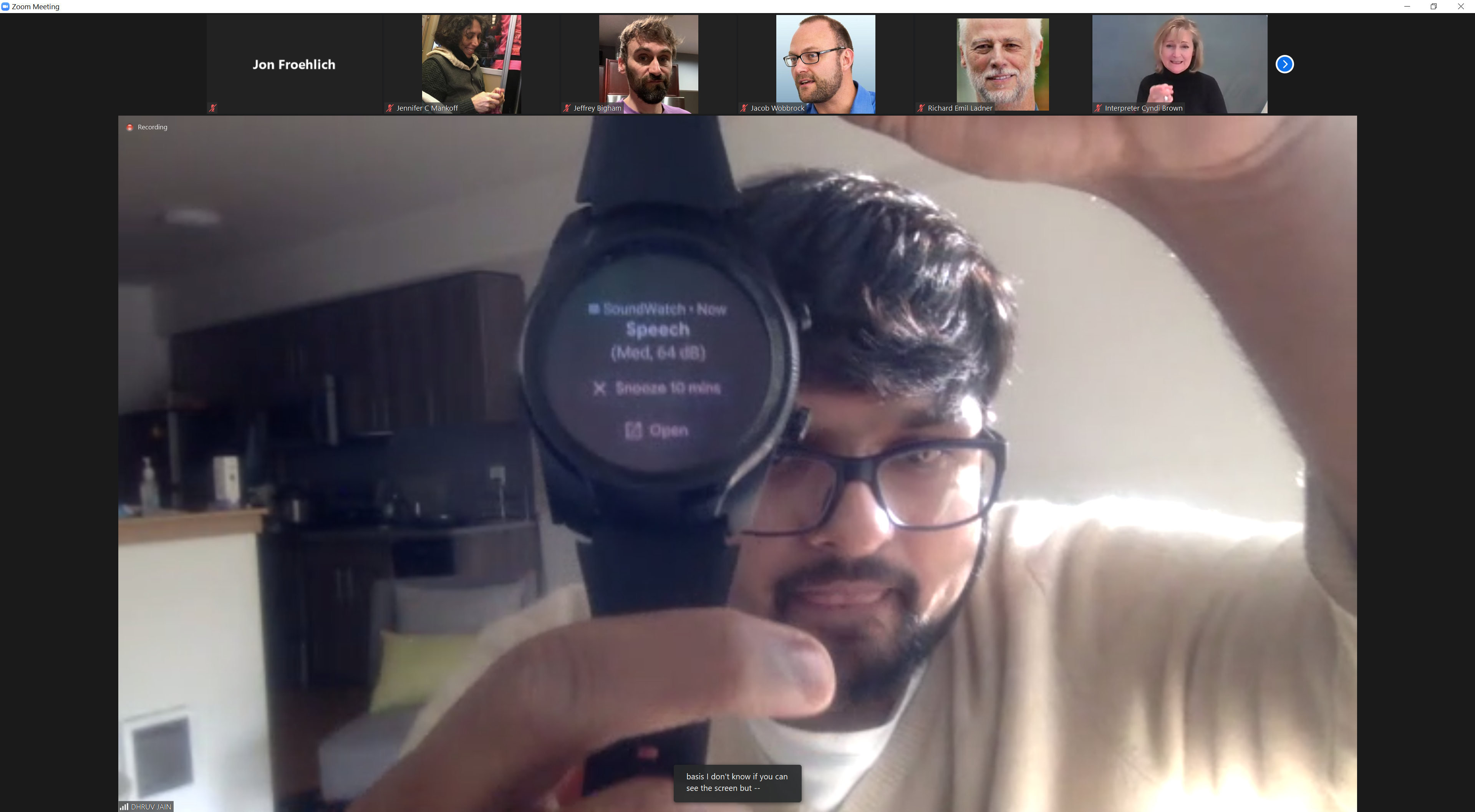 Image shows DJ holding an Android watch running the SoundWatch app, which has inferred that speech is inferring around him and shows this on the display