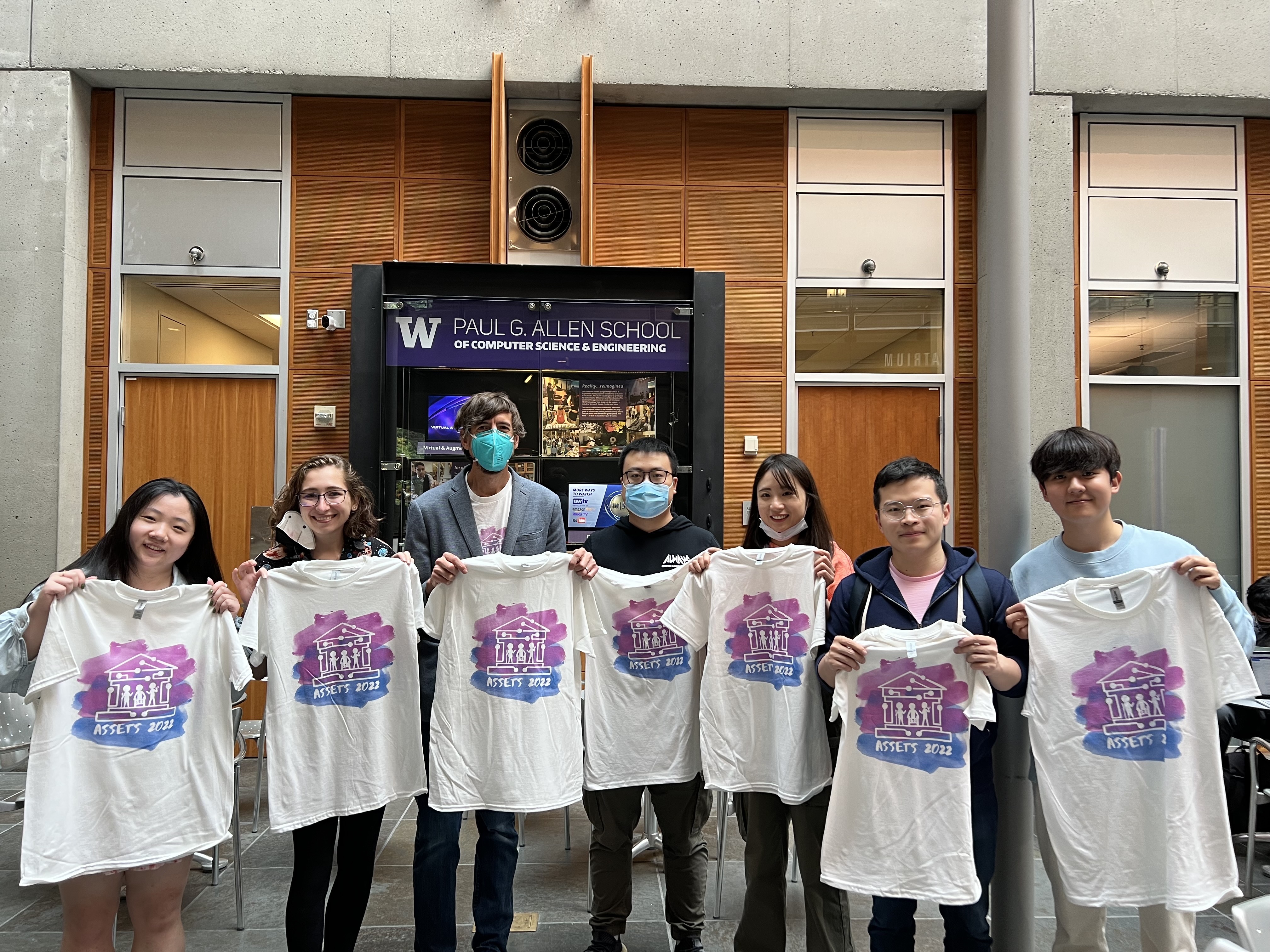 A picture of UW students holding up ASSETS'22 t-shirts