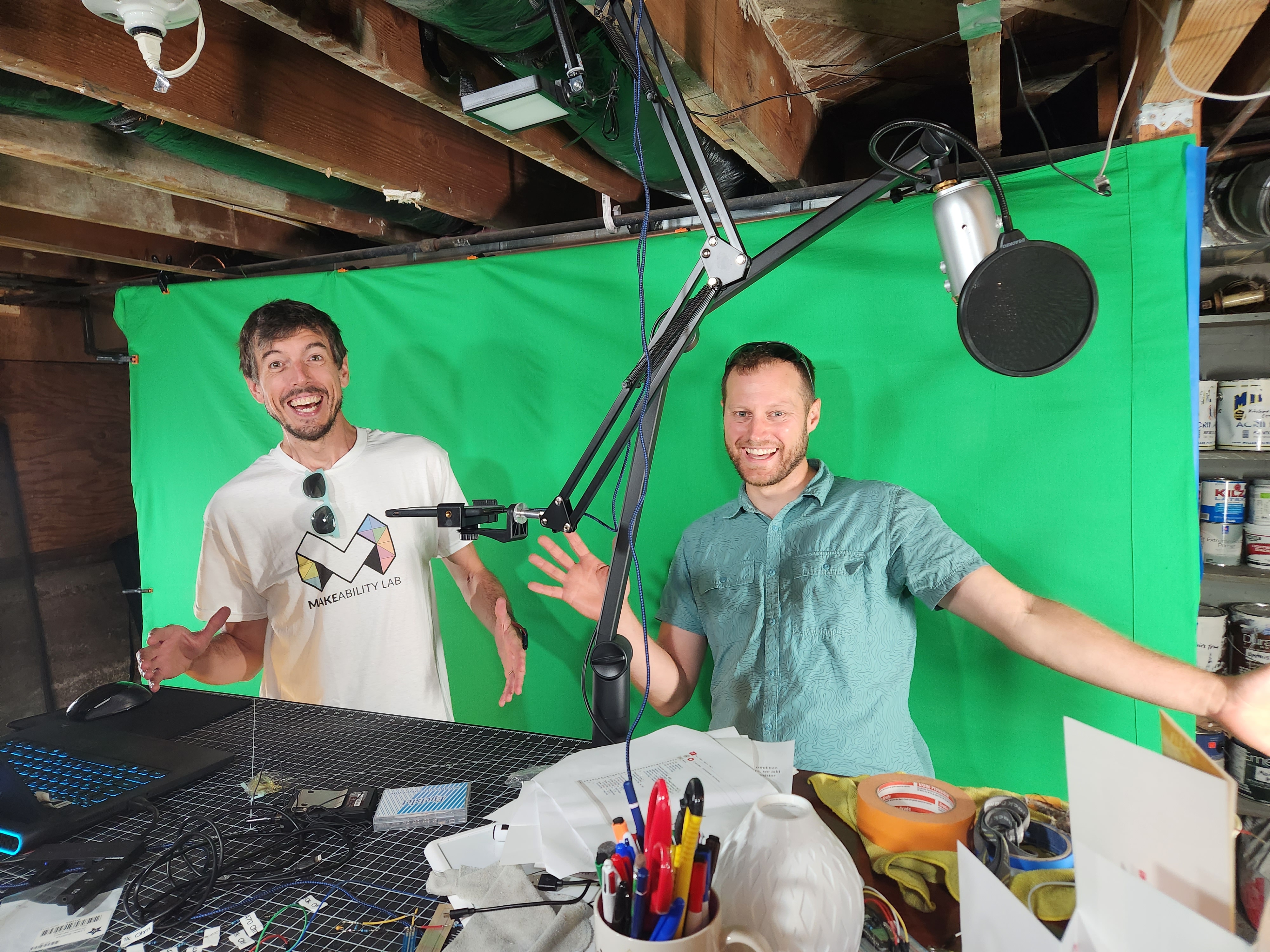 Jon and Brent standing in front of Jon's green screen and making funny gestures/faces